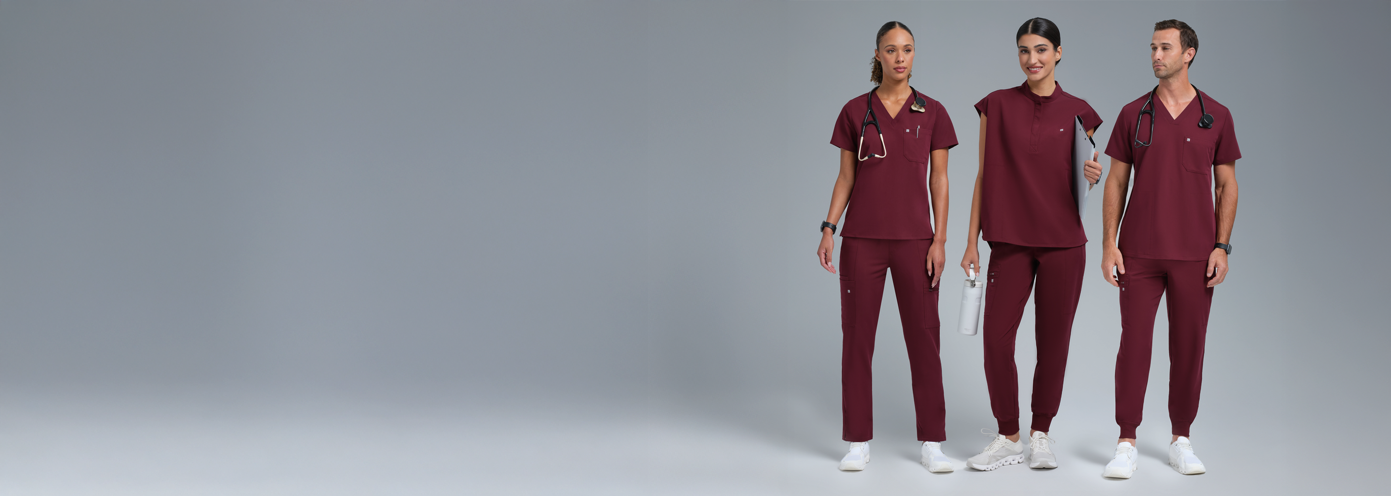 Three people wearing maroon scrubs on a gray background