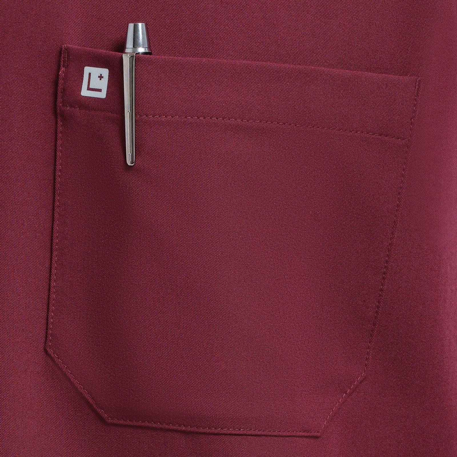 Close-up of a burgundy pocket with a pen and brand logo on a matching garment.