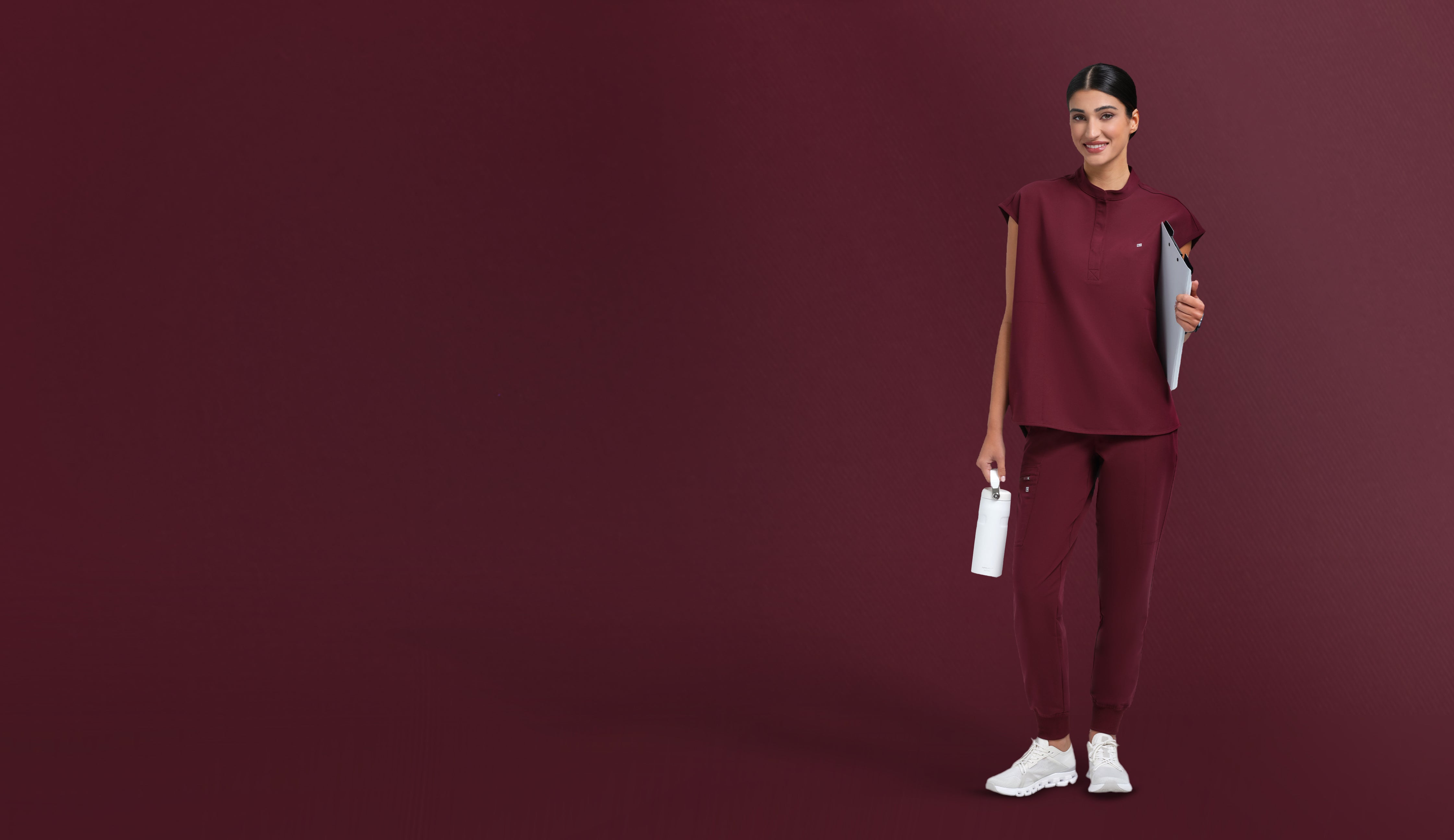 Person wearing a burgundy outfit holding a white box on a dark red background