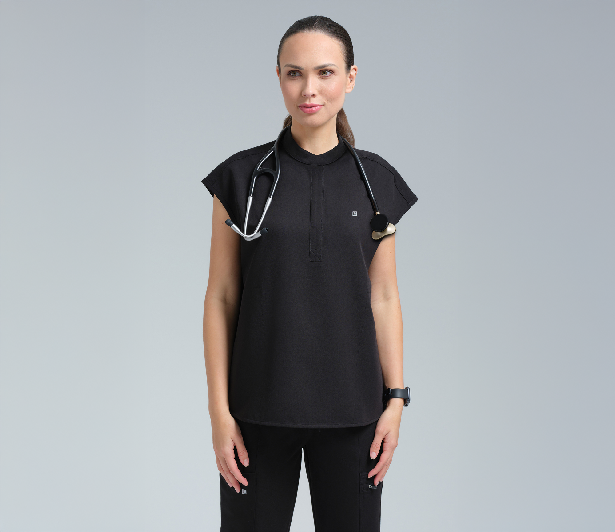 Woman wearing a black sleeveless top with decorative elements on a gray background